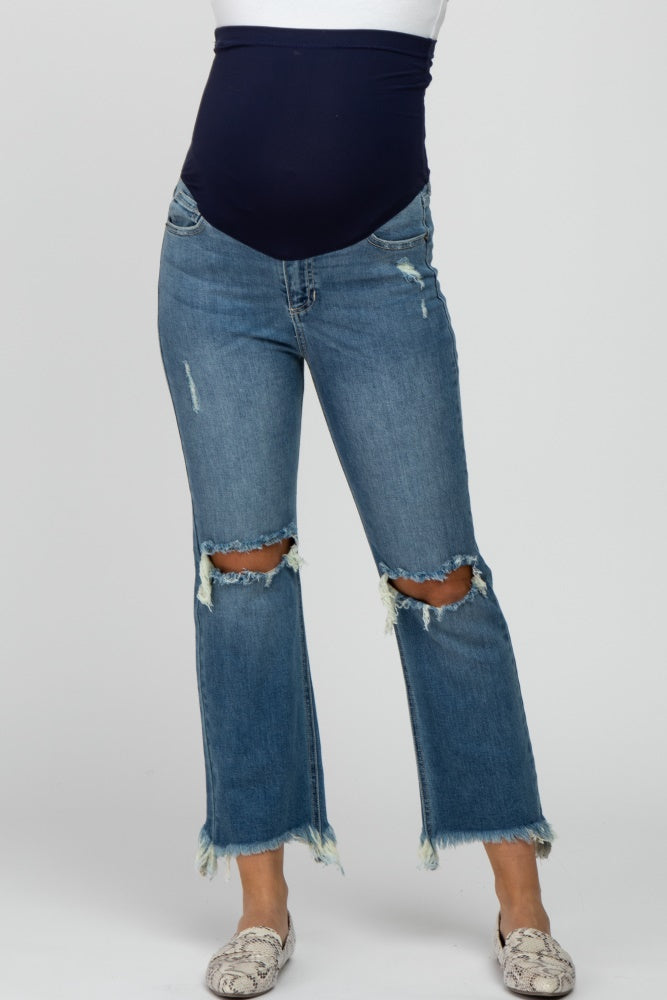 woman wearing a light blue distressed maternity jeans with a black belly band and frayed hems