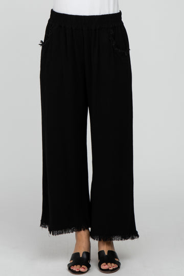 woman wearing black wide-leg pants with fringe hems and side pockets, styled with a simple white top