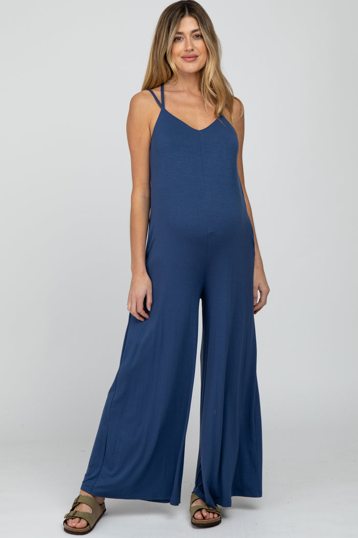 woman wearing a blue maternity jumpsuit with wide legs and adjustable straps, showcasing a visible baby bump