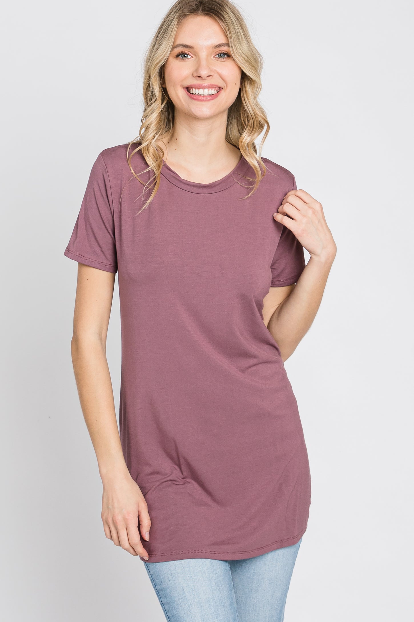 woman wearing a mauve short sleeve tunic top with a round neckline and relaxed fit, smiling at the camera