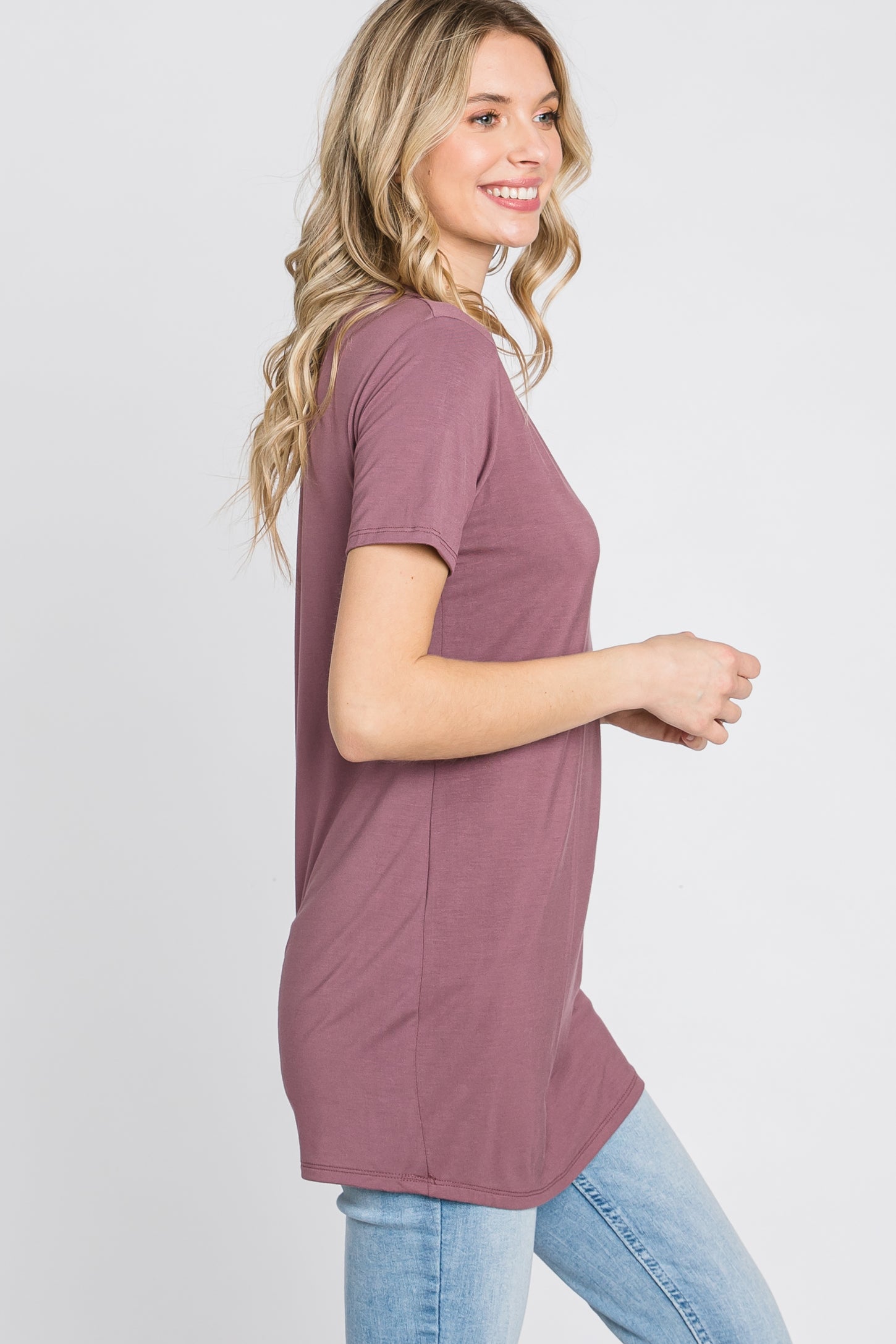 woman wearing a slim-fit mauve t-shirt with short sleeves and a rounded hem, paired with light blue jeans