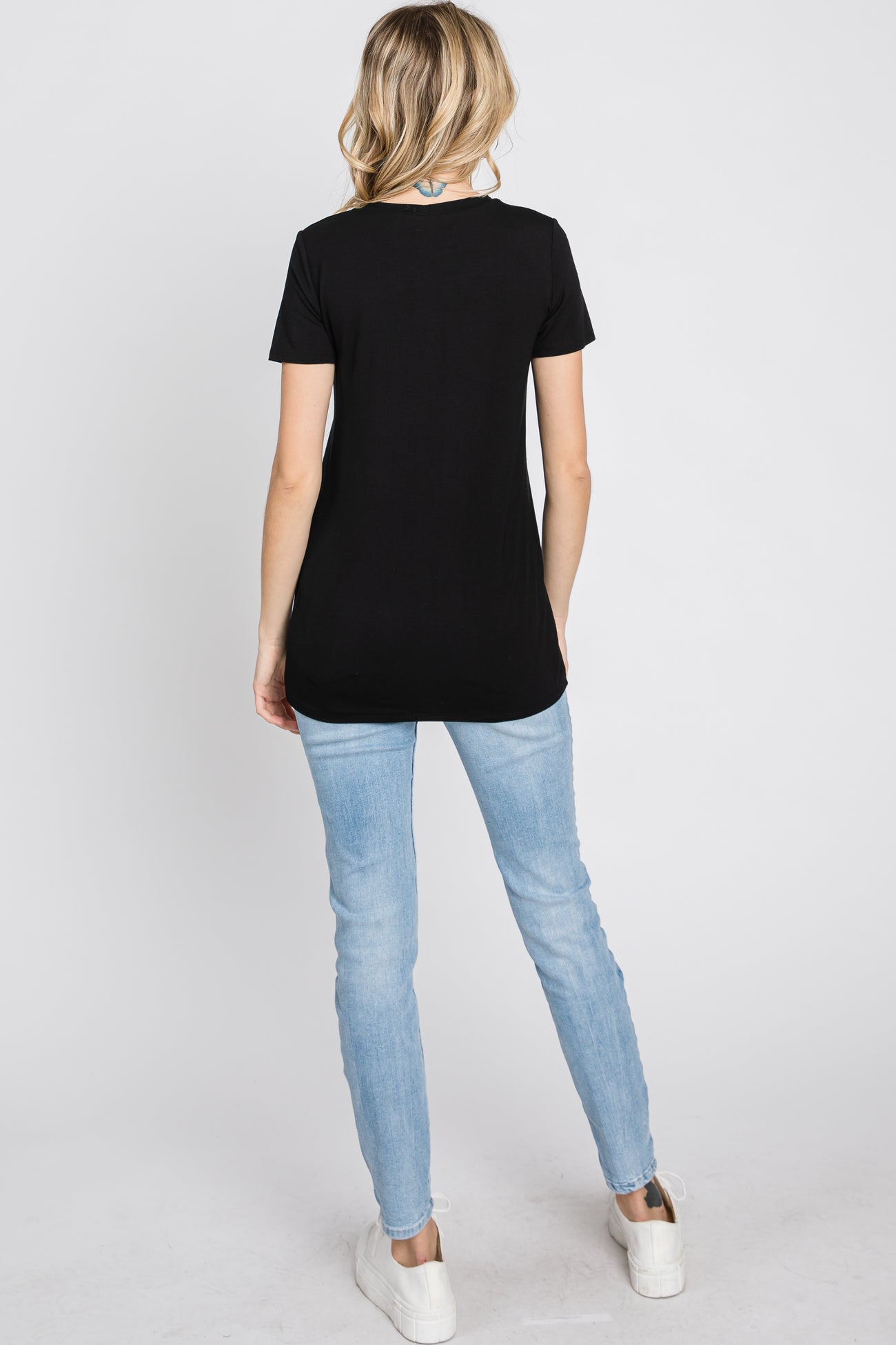 woman wearing a black short sleeve top and light blue skinny jeans, seen from the back