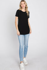 woman wearing a black short sleeve t-shirt and light blue skinny jeans, standing against a white background