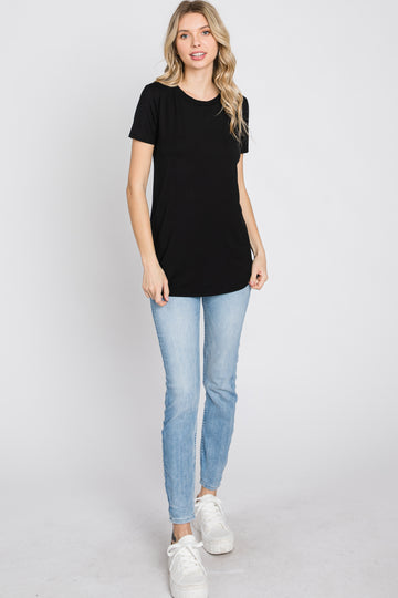 woman wearing a black short sleeve t-shirt and light blue skinny jeans, standing against a white background
