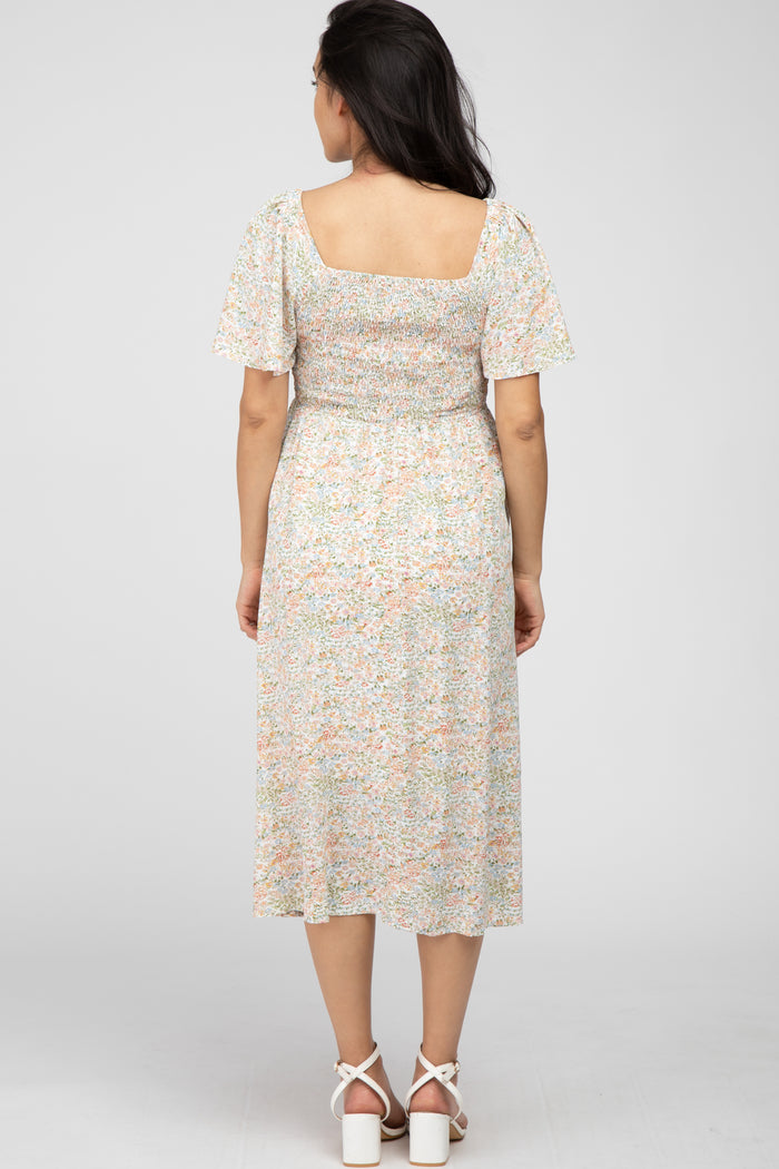 woman wearing a floral maternity dress with puff sleeves and a smocked bodice, view from the back
