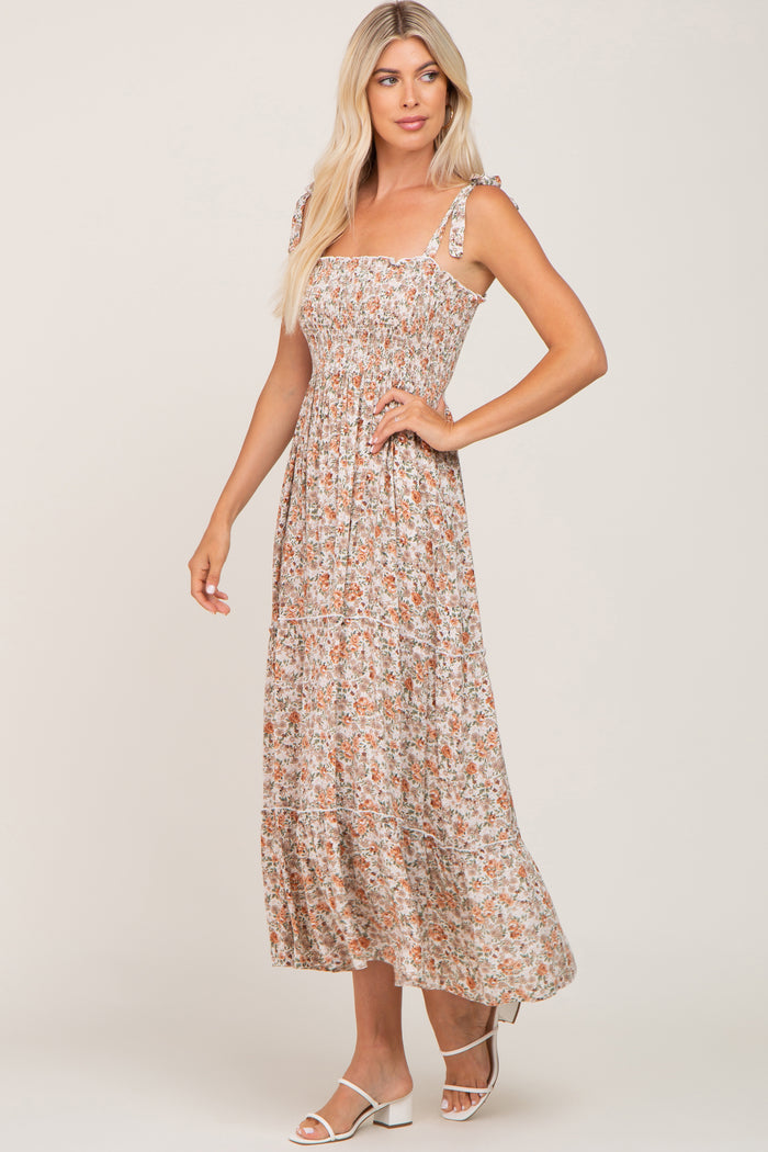 woman wearing a floral maxi dress with smocked bodice and tie straps, standing and smiling