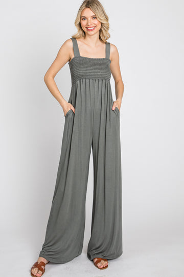 woman wearing a dark gray smocked bodice wide-leg jumpsuit with pockets
