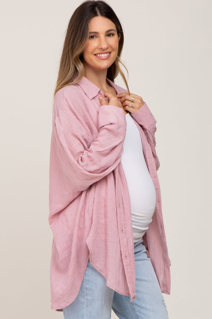 woman wearing a light pink maternity button-up shirt with a relaxed fit, showing her baby bump and paired with light blue jeans