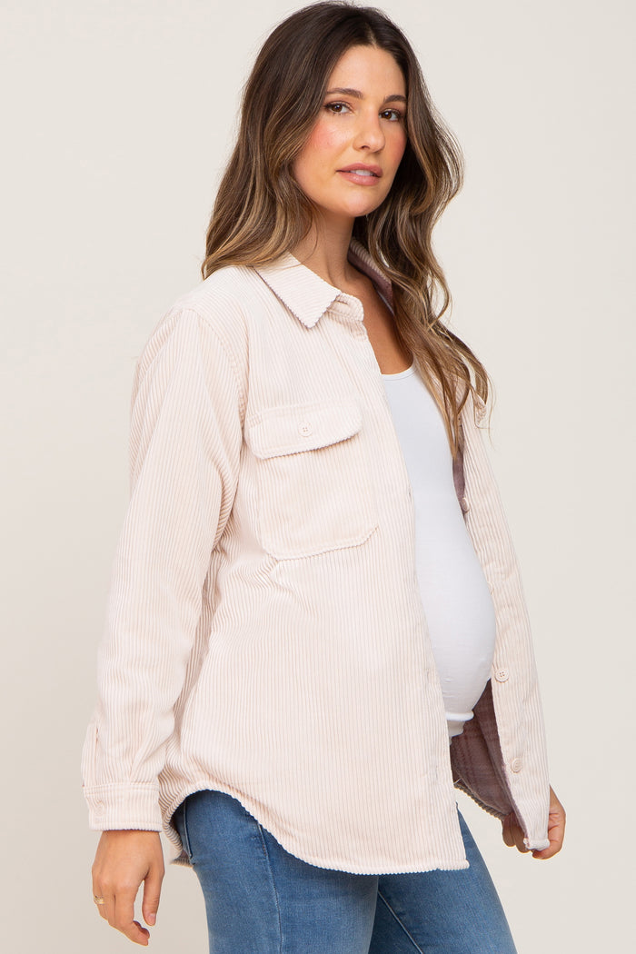 Pregnant woman wearing a light pink corduroy maternity shirt over a white tank top and blue jeans