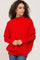 woman wearing a red oversized knit sweater with a high neckline and relaxed fit, styled with denim jeans