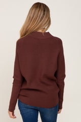 woman wearing a maroon maternity sweater, viewed from the back, styled with blue jeans