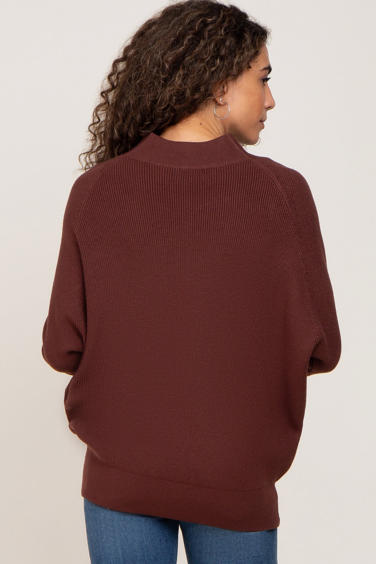 woman wearing a brown oversized ribbed sweater, seen from the back, with a relaxed fit and wide neckline