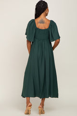 woman wearing a dark green textured midi dress with puff sleeves, showing a tattoo on her back