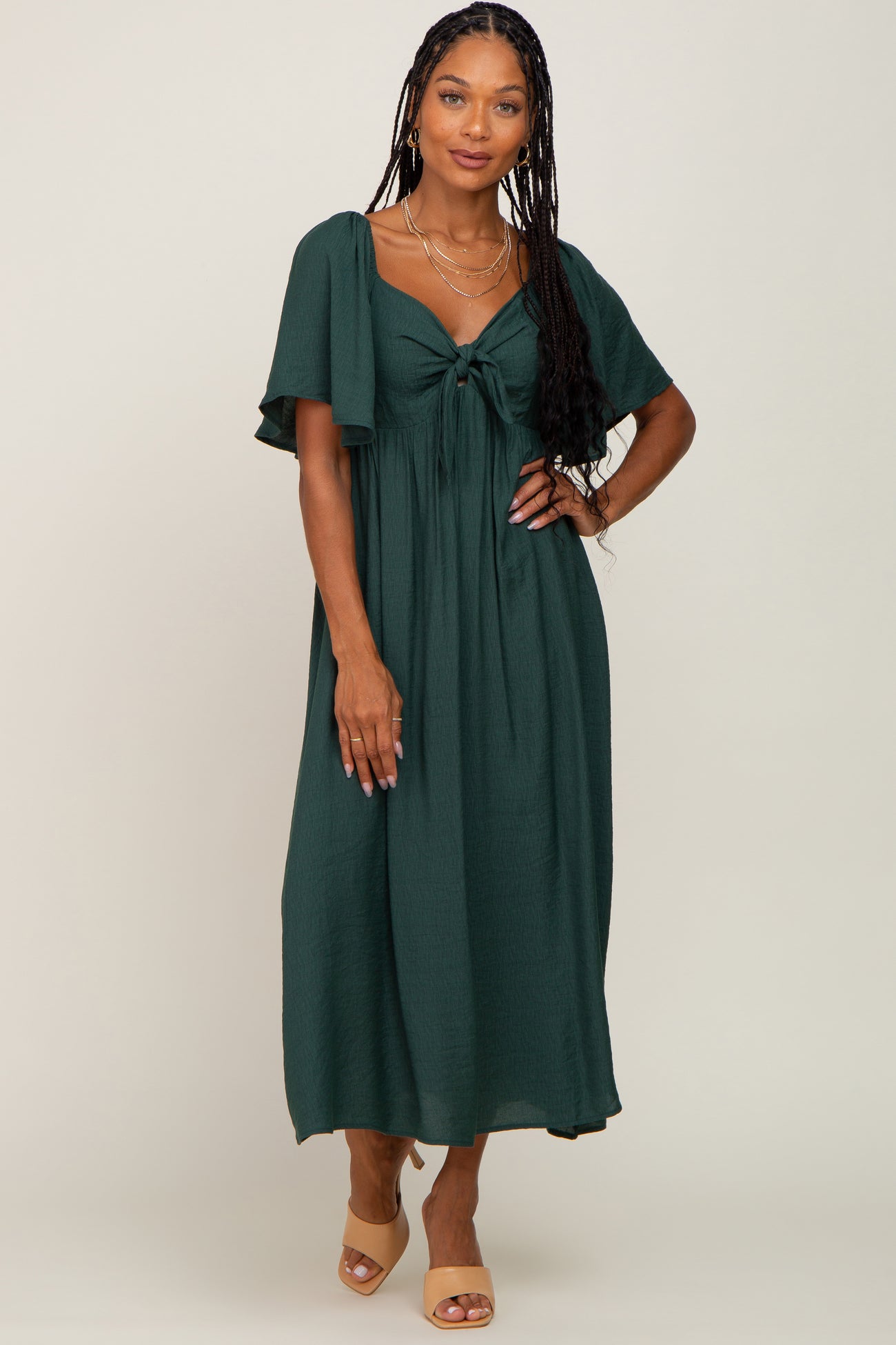 woman wearing a dark green maxi dress with a tied front detail and short flutter sleeves