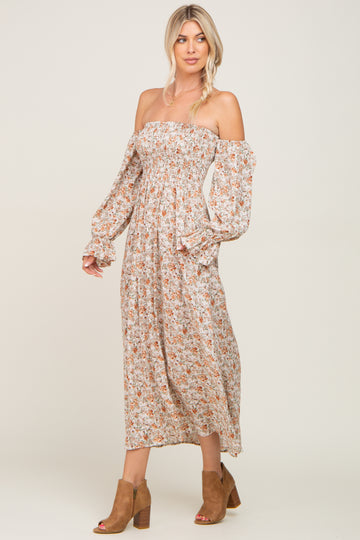 woman wearing a floral off-the-shoulder maxi dress with long sleeves and a fitted bodice, paired with brown ankle boots
