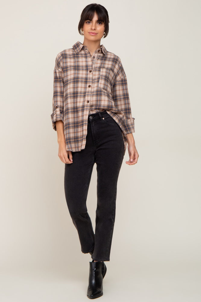 woman wearing an oversized tan and blue plaid flannel shirt with high-waisted black jeans and boots