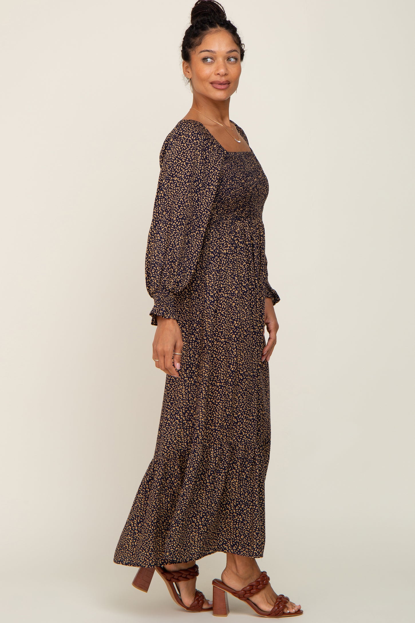 woman wearing a long sleeve leopard print smocked maxi dress and brown braided heels