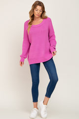 woman wearing a bright pink oversized sweater with a scoop neckline and blue skinny jeans, paired with white sneakers
