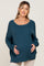 woman wearing a teal maternity sweater with a relaxed fit and holding her baby bump