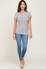 woman wearing a gray short sleeve tee and skinny jeans, standing and smiling at the camera