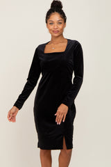 woman wearing a long sleeve black velvet midi dress with a square neckline and side slit