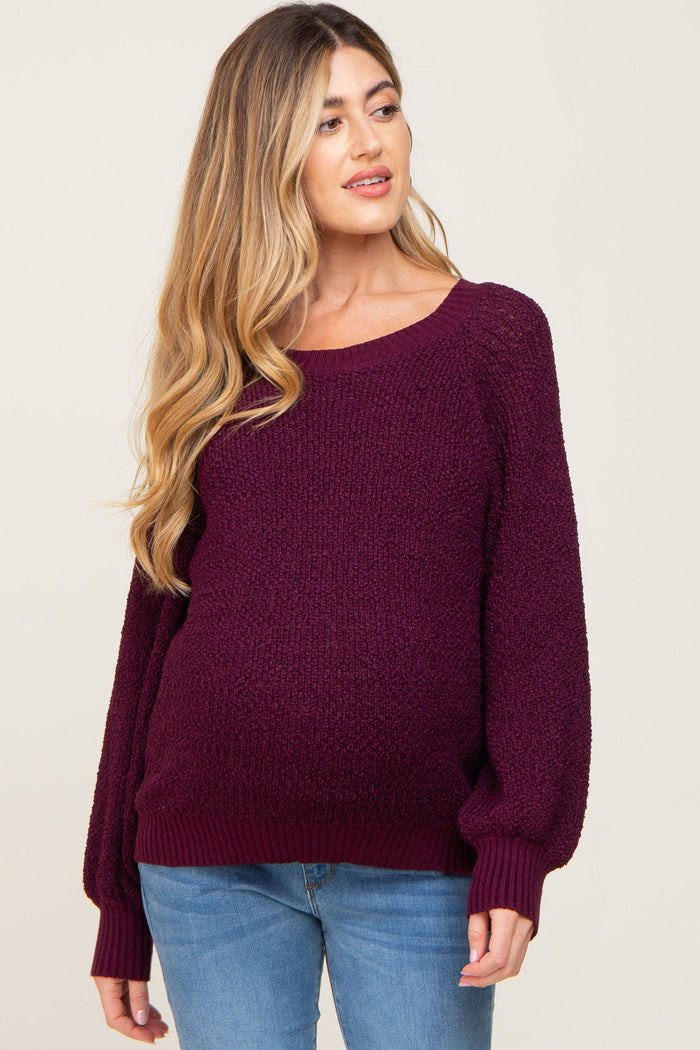 woman wearing a burgundy chunky knit maternity sweater with a relaxed fit and a visible baby bump