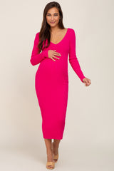 woman wearing a hot pink ribbed maternity dress with long sleeves and a v-neck, gently holding her baby bump