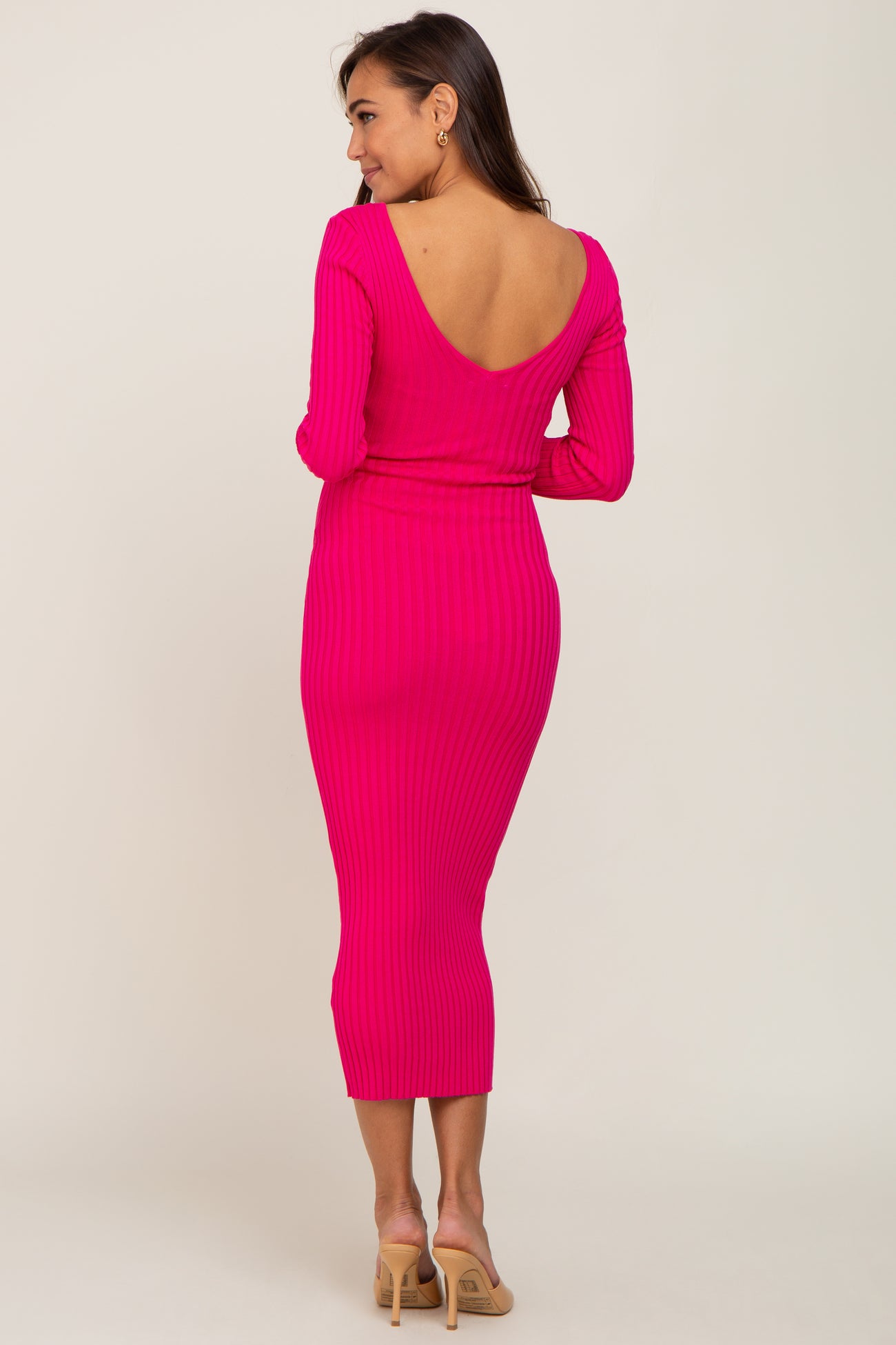 woman wearing a hot pink ribbed maternity dress with a deep v-back and fitted silhouette