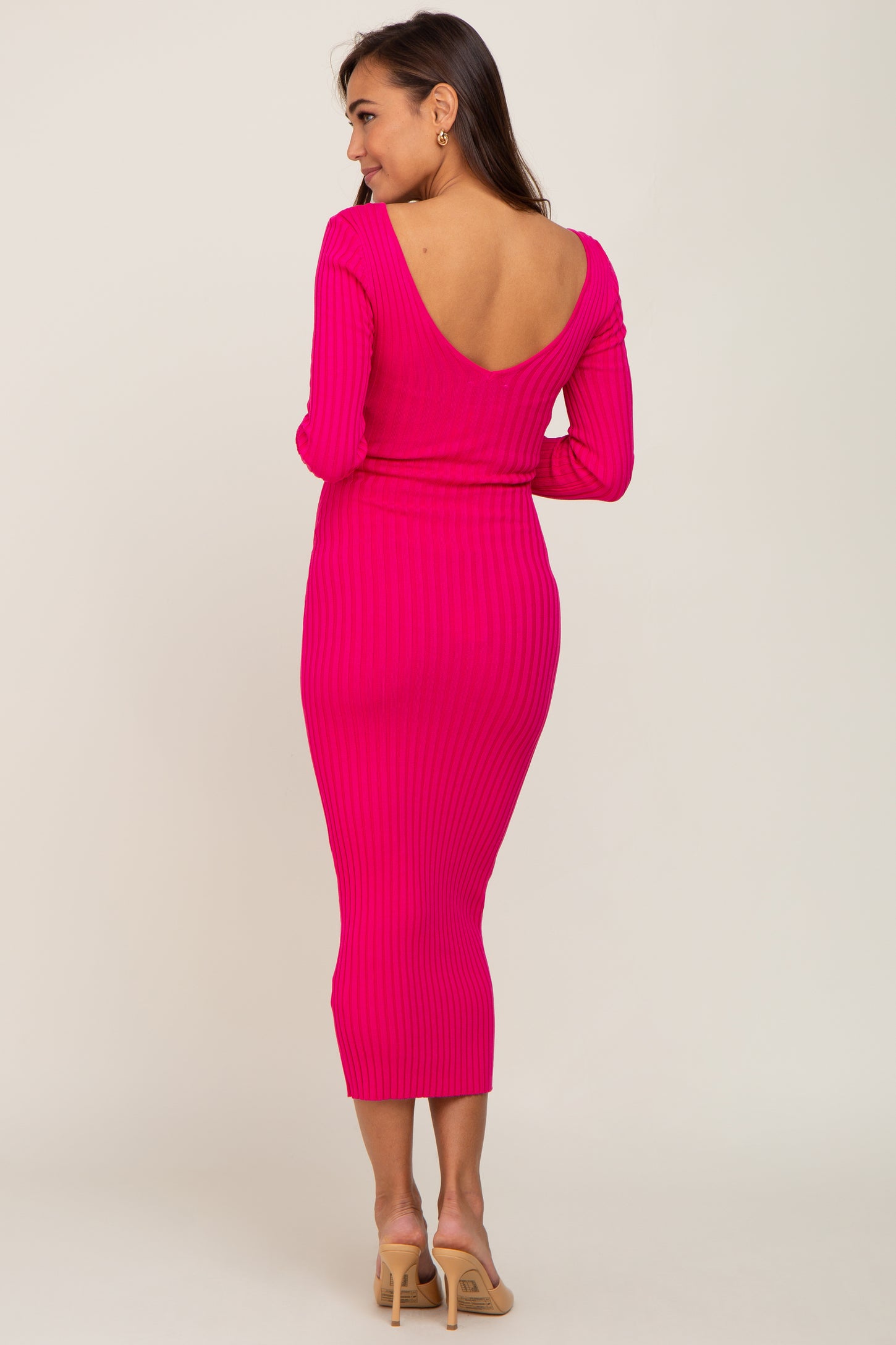woman wearing a hot pink ribbed maternity dress with a deep v-back and fitted silhouette