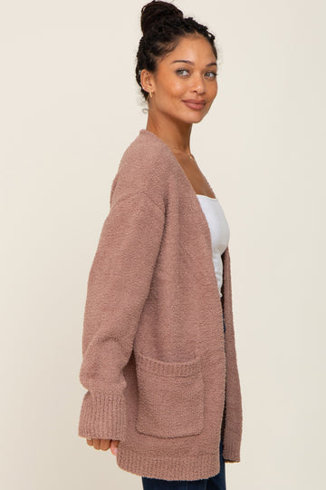 Woman wearing a mauve fuzzy knit cardigan with front pockets over a white top