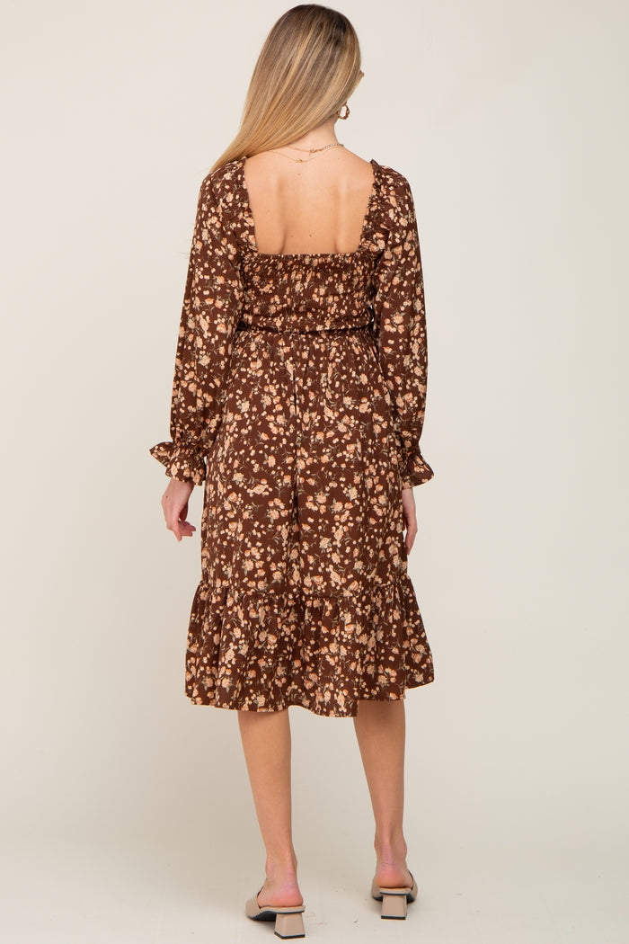woman wearing a brown floral long sleeve maternity dress with a fitted bodice and ruffled hem