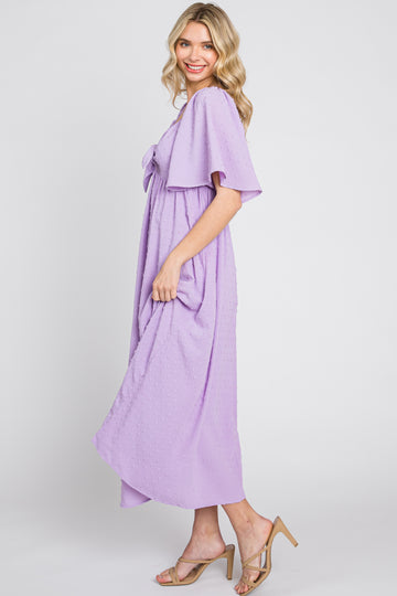 woman wearing a lavender short sleeve maxi dress with a bow detail and a flowing silhouette