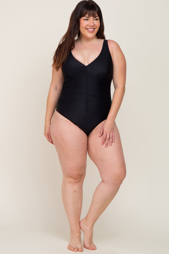 smiling woman wearing a black one-piece swimsuit with a v-neckline and ruched bodice