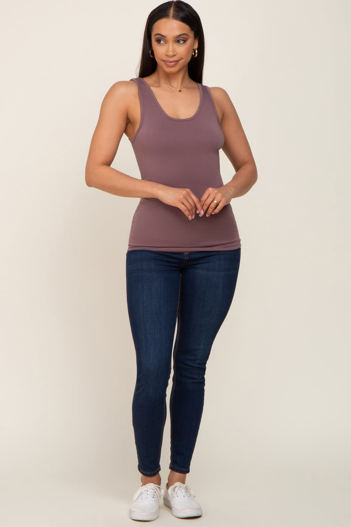 woman wearing a mauve racerback tank top with blue skinny jeans and white sneakers