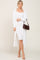 woman wearing a white ribbed midi dress paired with a long white cardigan and holding a brown handbag