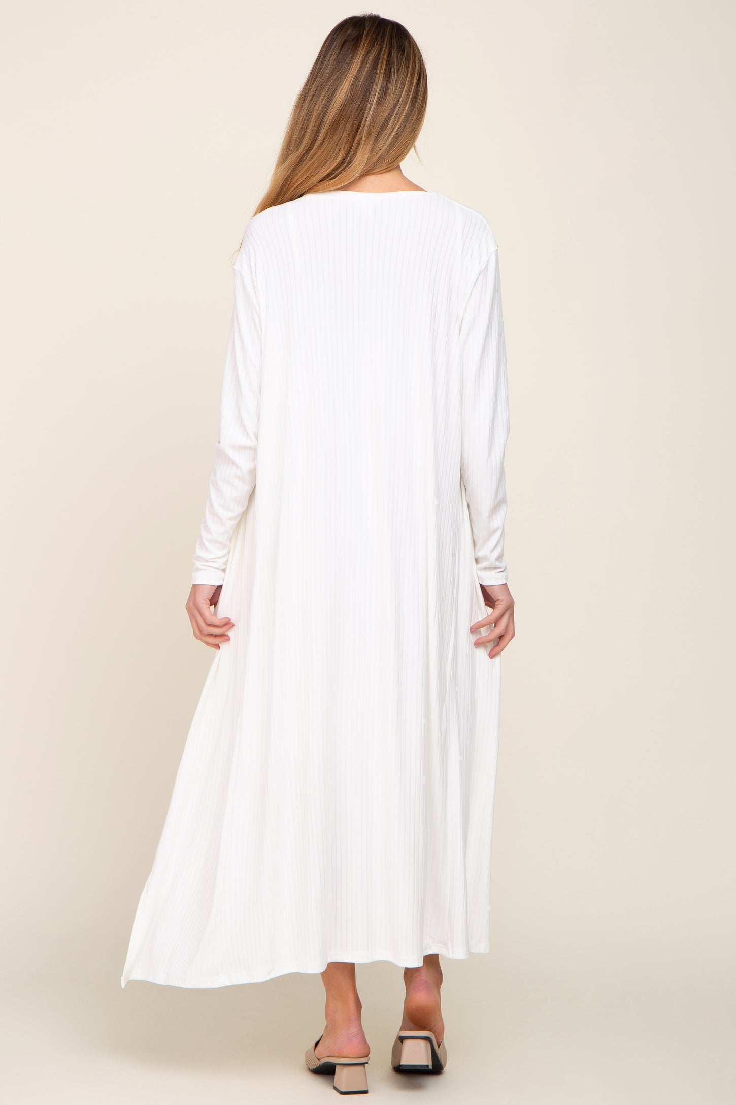 woman wearing a long white ribbed maternity dress with long sleeves, seen from the back