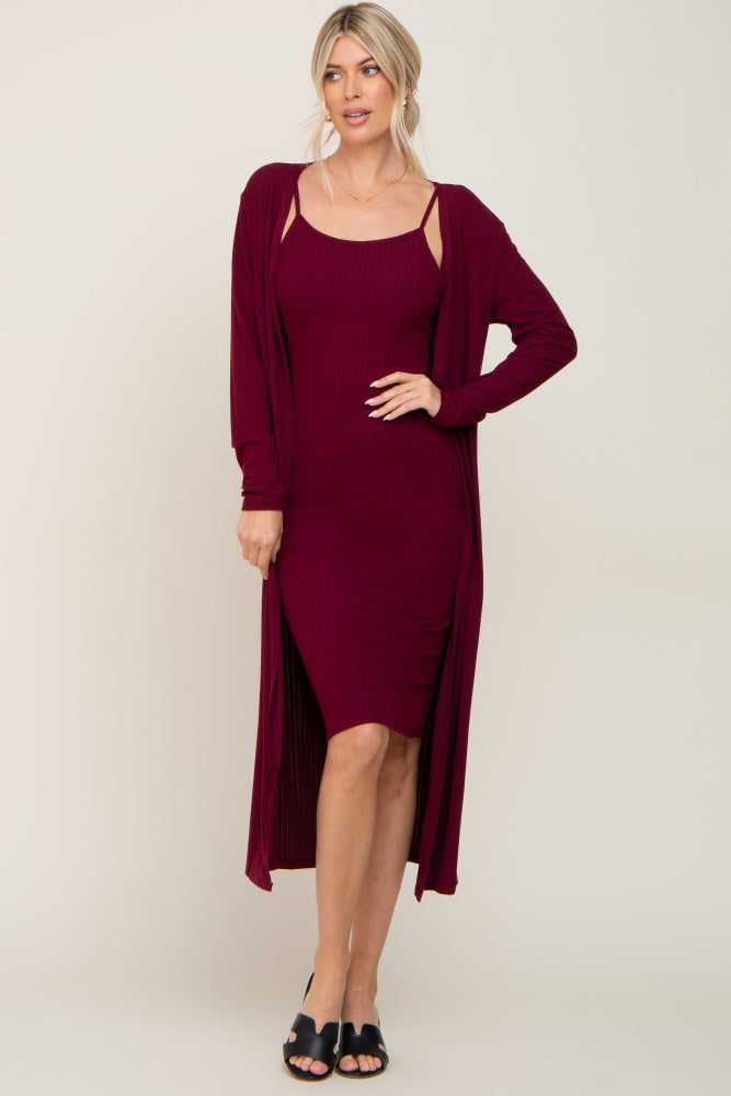 woman wearing a burgundy ribbed dress with side cutouts and a matching long cardigan, styled with black slip-on shoes