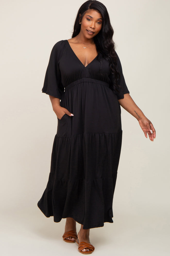 woman wearing a black tiered maxi dress with a deep v-neck and short sleeves, featuring pockets