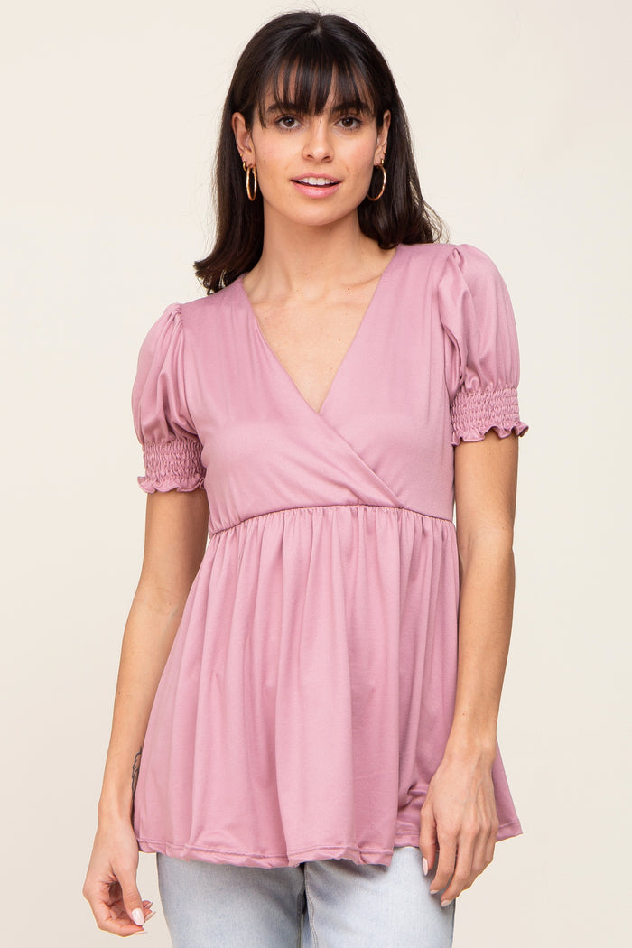 woman wearing a pink v-neck top with puff sleeves and gathered details, styled with light blue jeans