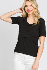 woman wearing a black ribbed short sleeve top with a layered design and smiling