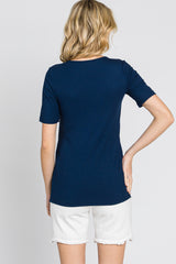 woman wearing a navy blue ribbed short sleeve top and white denim shorts, seen from the back