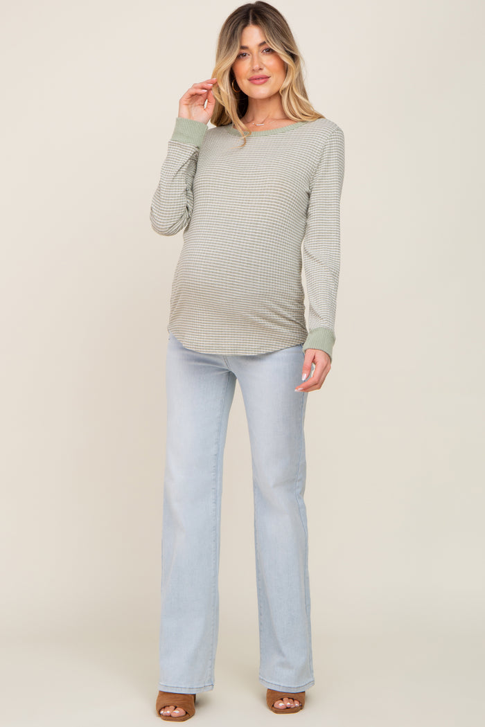 Pregnant woman wearing a green striped long sleeve maternity top and light wash flare jeans