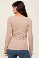 woman wearing a beige long sleeve fitted top with a scoop back, standing with her back to the camera in blue jeans