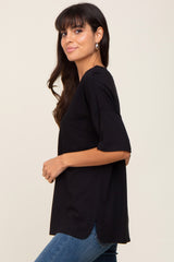 woman wearing a black short sleeve top with a front pocket and a loose fit, paired with blue jeans