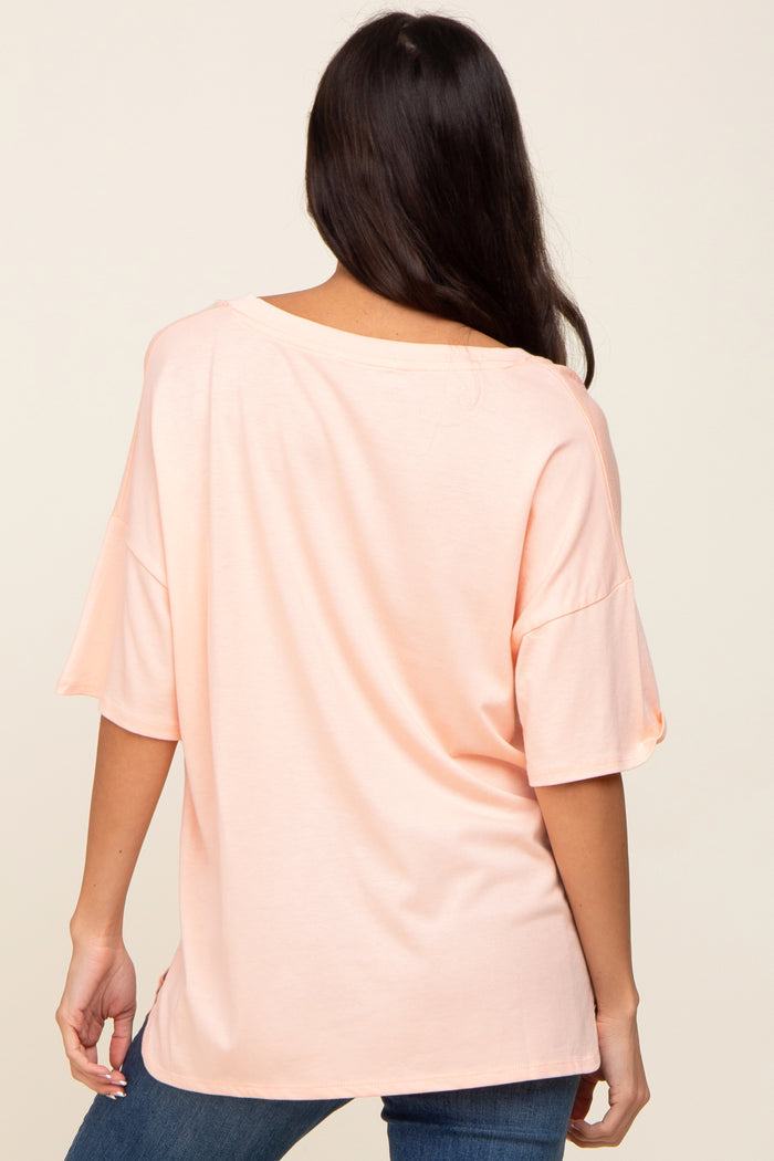 back view of a woman wearing a light peach short sleeve oversized t-shirt and blue jeans