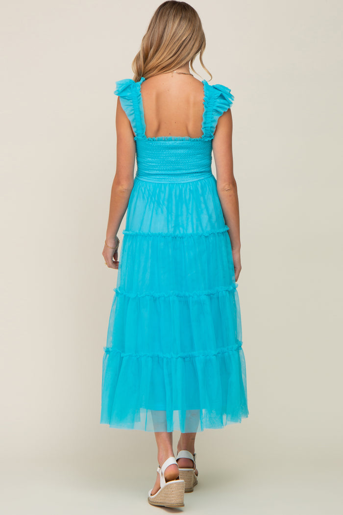 woman wearing a teal tiered maxi maternity dress with ruffle straps and a smocked bodice, showcasing a baby bump