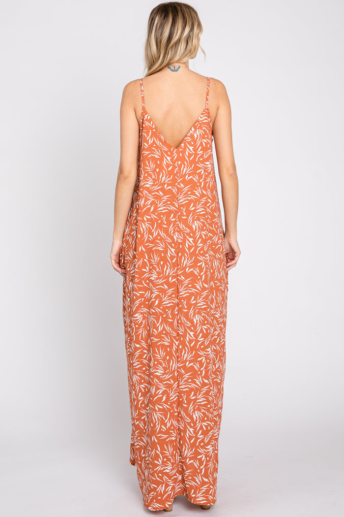 woman wearing a rust orange floral maxi dress with a low back and thin straps