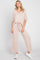 woman wearing a loose-fitting light pink jumpsuit with a v-neck and wide-leg pants, paired with white sneakers