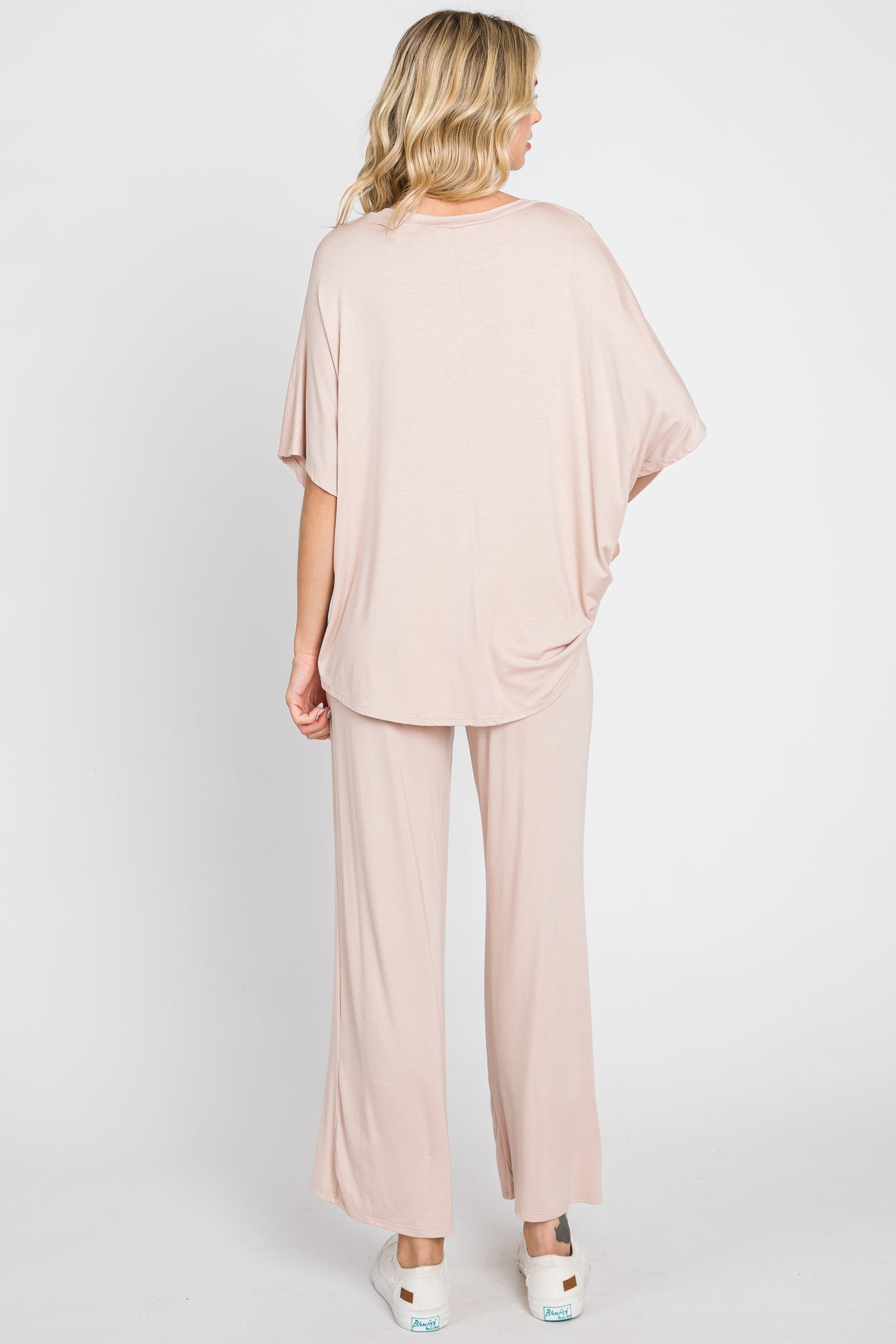 woman wearing a light pink oversized top and matching wide-leg pants, viewed from the back