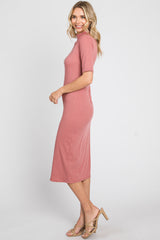 woman wearing a dusty rose ribbed midi dress with short sleeves and a high neckline, standing sideways in sandals